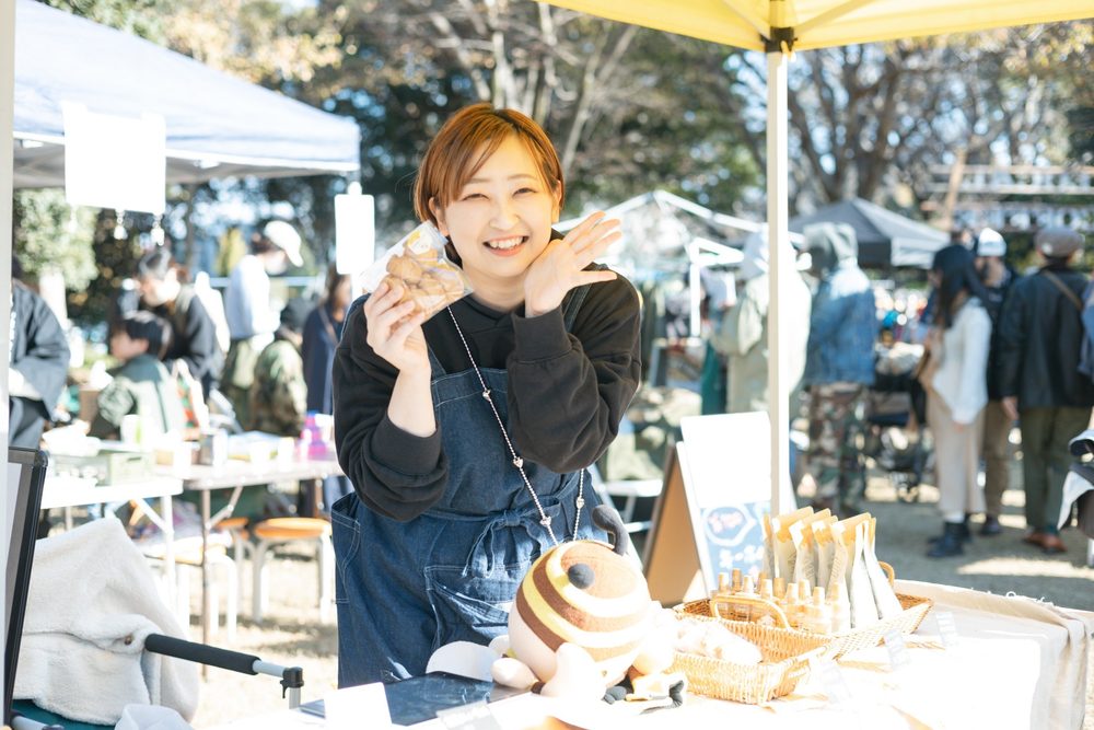 商品を手に笑顔を見せる出店者